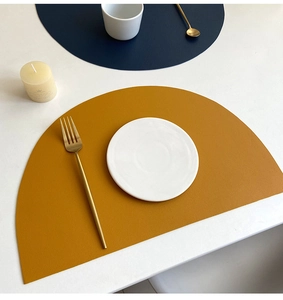 Detail of semi-circular PU leather placemats in ginger and blue with waterproof texture