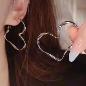 Detail view of silver heart hoop earrings showing the polished finish and wearing size