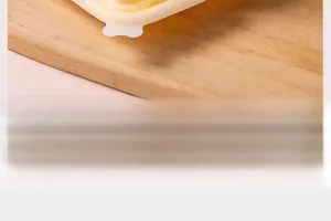 Detail view of a white silicone bear-shaped ice mold on a wooden board with soft lighting
