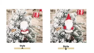 Close-up of plush Christmas gnomes with long legs hanging on a snowy Christmas tree branch