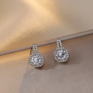 Détail de boucles d'oreilles argentées avec halo hexagonal sur tissu en soie dorée
