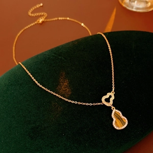 Close-up of gold gourd pendant with tiger eye stone and zircon on velvet pad