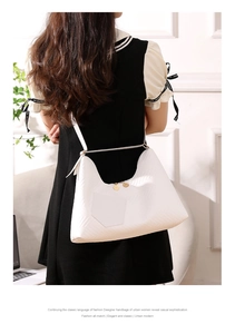 Detail shot of white shoulder bag with embossed chevron pattern and gold metal hardware