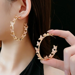 Détail des boucles d'oreilles créoles dorées en C avec papillons en strass rose