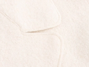 Macro shot of off-white wool fabric texture and fine stitching on a long winter coat
