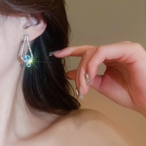 Close-up of A-line drop earrings with sparkling diamonds and elegant blue gemstones