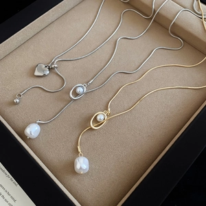 Detailed view of elegant snake chain necklaces with baroque pearl and heart pendants