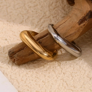 Minimalist dome ring set in polished 18K gold and silver finishes on a wooden branch