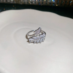 Detailed macro view of silver leaf ring with sparkling clear zircon stones on ceramic tray