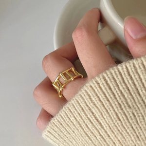 Detail of minimalist hollow golden geometric ring on model holding a white ceramic cup