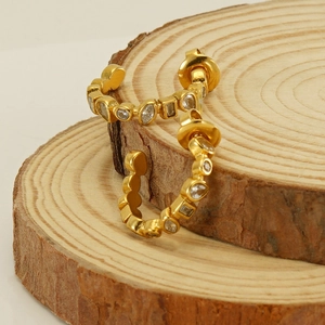 Close-up of gold U-shaped earrings with multi-cut crystals on a natural wood surface