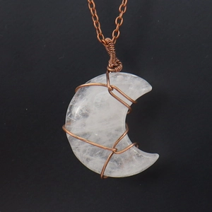 Macro detail of moon-shaped crystal pendant with handcrafted copper wire wrap and chain