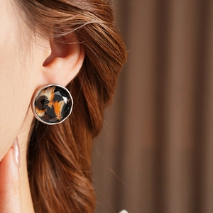 Close-up of leopard print round faceted earring with silver metal frame on model's ear