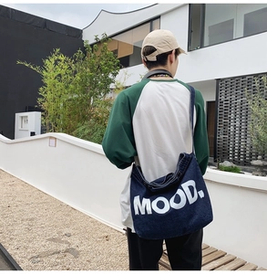 Rear view of large dark blue denim crossbody bag with white MOOD text on model