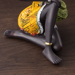 Detailed macro view of resin African figurine with yellow textured skirt and gold anklet