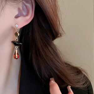 Dettaglio di orecchini pendenti asimmetrici vintage con perle di cristallo e zircone