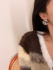 Close-up of a silver-toned twisted hollow flower earring worn on a model's ear