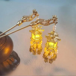 Detail of golden ancient Chinese hairpins with glowing lantern tassels and faux pearls
