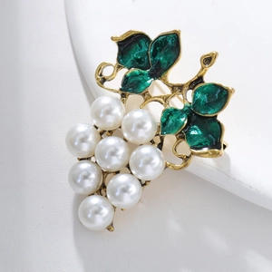 Macro detail of vintage grape brooch with green enamel leaves and ten white pearls