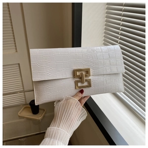 Detail of white crocodile pattern envelope clutch bag with gold geometric metal buckle