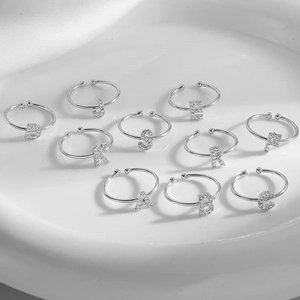 Silver copper letter rings A-J with cubic zirconia on white silk background
