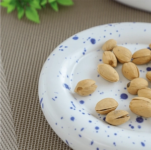 Macro shot of white ceramic plate with blue speckles and glossy finish for breakfast