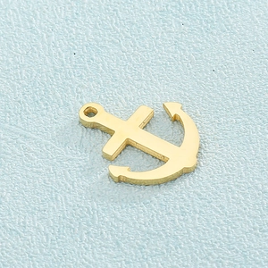 Golden stainless steel anchor pendant necklace on a textured light blue background