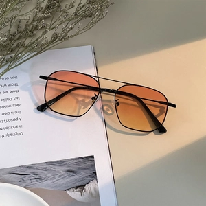 Retro double-bridge metal sunglasses with orange gradient lenses on a lifestyle magazine