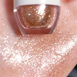 Primo piano di un ombretto liquido glitter oro rosa sulla pelle con texture scintillante