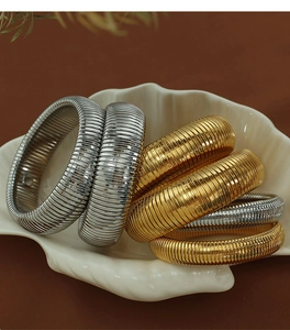 Artistic display of 20mm textured stretch bracelets in gold and silver on a shell tray