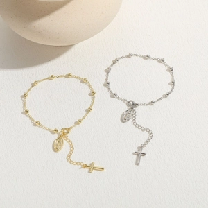 Detail of 14K gold and silver rosary bracelets with cross and Virgin Mary pendants