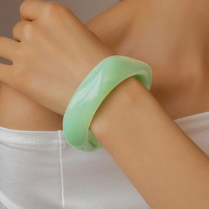 Detailed shot of a chunky light green resin wavy bangle with a smooth translucent finish