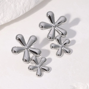Polished silver stainless steel double flower stud earrings on white stone background