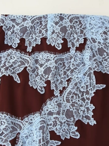 Détail de la dentelle florale bleu clair avec doublure bordeaux et bordure en cils fins