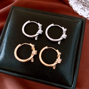 Detail of 18k gold and silver knot hoop earrings with paved cubic zirconia stones