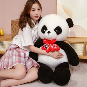 Close-up of a large panda plush toy with a red bow tie featuring a heart-shaped pattern