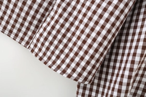 Macro detail of brown and white gingham woven cotton fabric with fine hem stitching