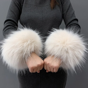 Close-up of soft white faux fur wrist cuffs shown on a model with a grey background