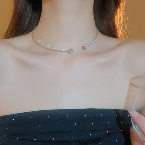 Close-up of heart-shaped pink crystals on a silver open choker necklace worn by a model