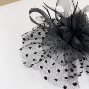 Detail of vintage black polka dot mesh veil with elegant fabric flower and feather accents