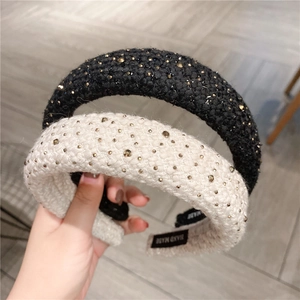 Close-up of thick tweed braided headbands with golden studs in black and beige