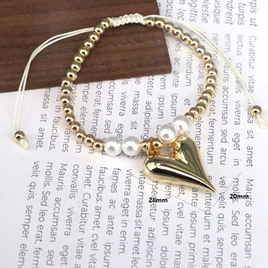 Detail view of a beaded bracelet with a large 28mm gold heart charm and pearl beads