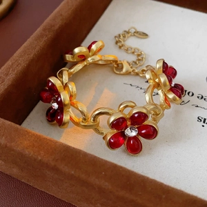 Macro view of vintage gold bracelet with red floral charms and crystals in velvet box