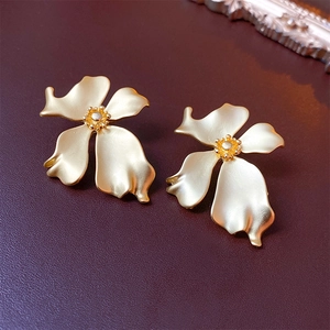 Close-up of vintage golden flower stud earrings with a matte metallic texture