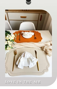 Detail of orange and beige faux leather placemats with irregular wavy edges and textures