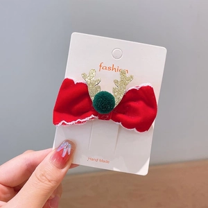 Dettaglio molletta per capelli con fiocco di Natale in velluto rosso e corna dorate