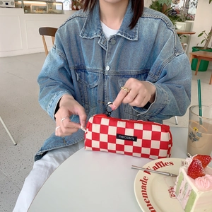 Detail of red and white checkered corduroy makeup pouch with zipper and logo