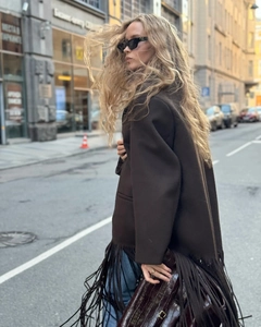Detailed view of long fringes on a dark brown oversized woolen jacket with urban styling