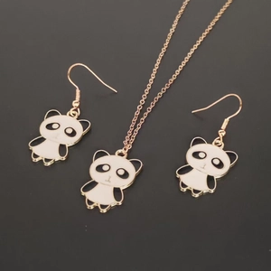 Close-up of golden panda jewelry set with black and white enamel pendant and earrings