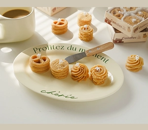 Velas aromáticas con forma de galleta en un plato de cerámica con caja de regalo